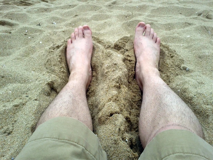 a man's legs and feet in the sand