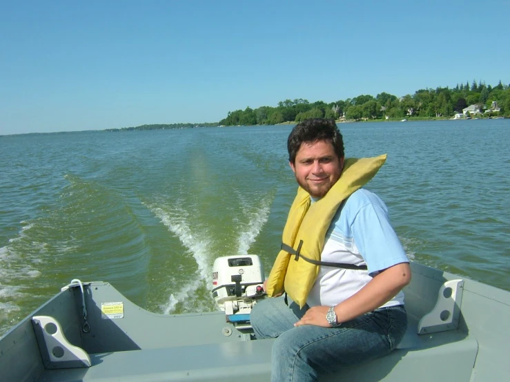 a man smiling while sitting on a boat holding a banana