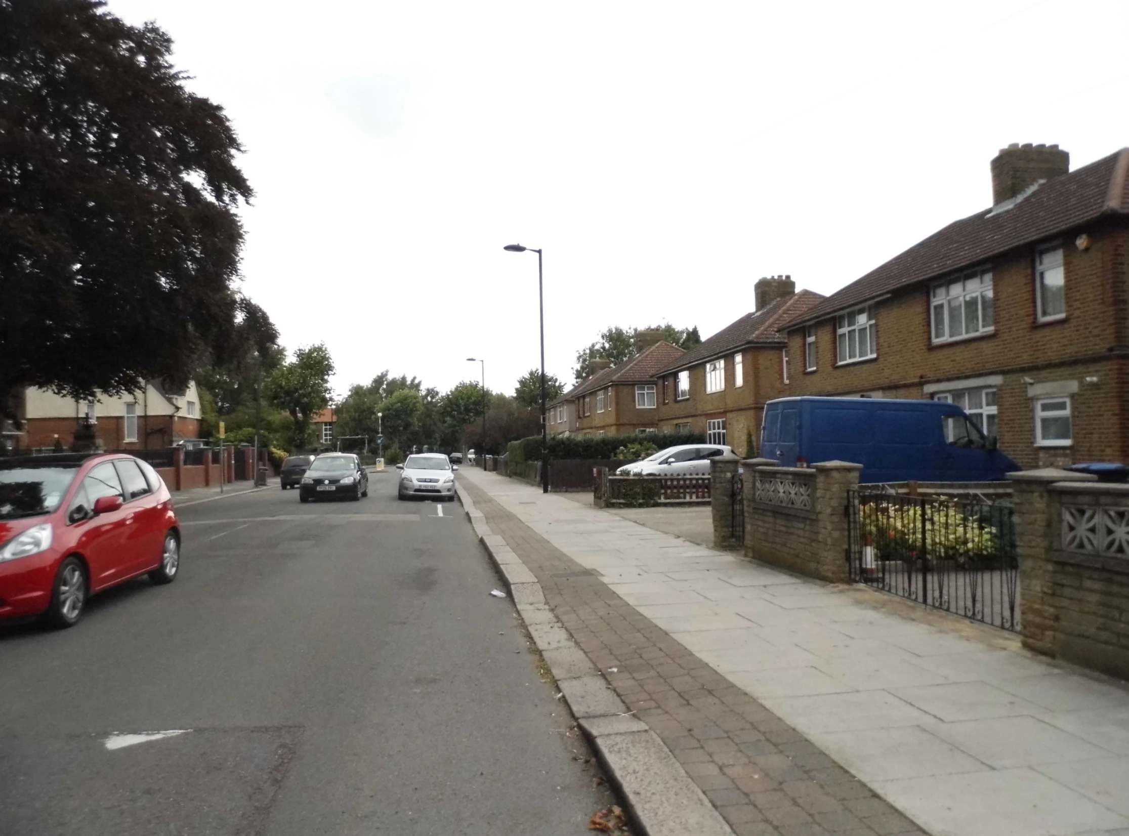 a road lined with brick homes with cars parked nearby