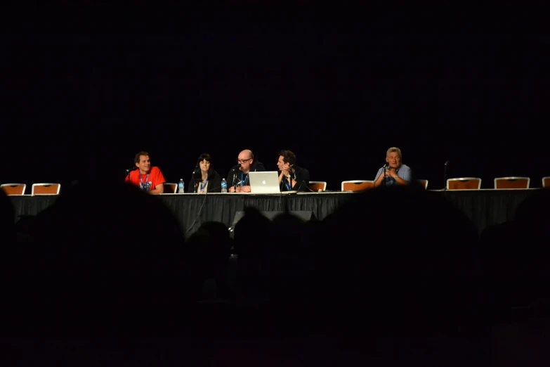 several people are sitting at a table during a panel