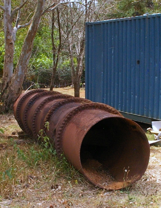 a rusty pipe is next to a tree and a large box