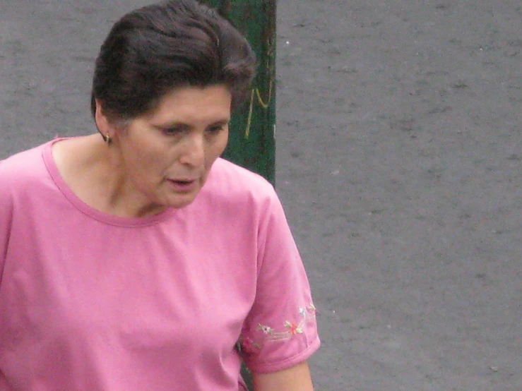 a woman in a pink shirt walking along a sidewalk