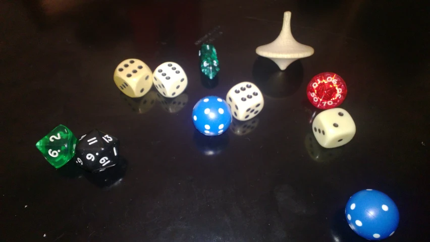 many different dice on a dark surface with the reflection of the dice