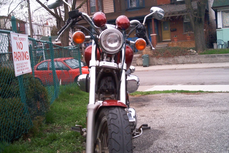 a motorcycle parked in front of a fence near a street