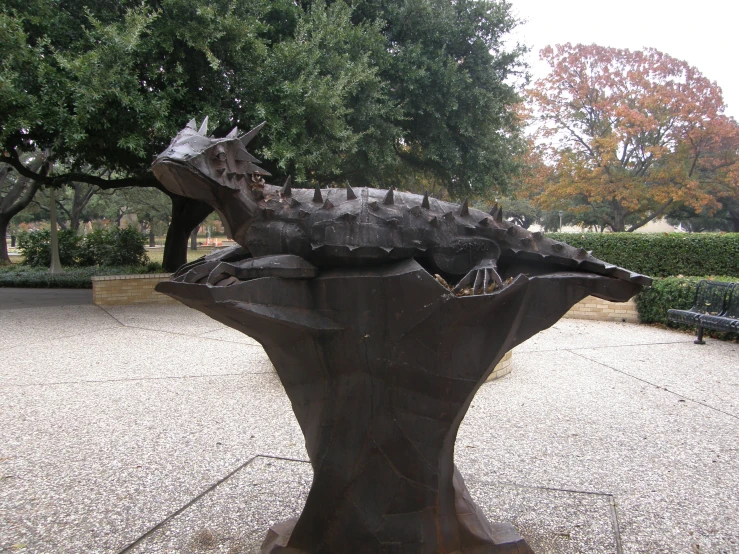 a statue of a lizard in a park area