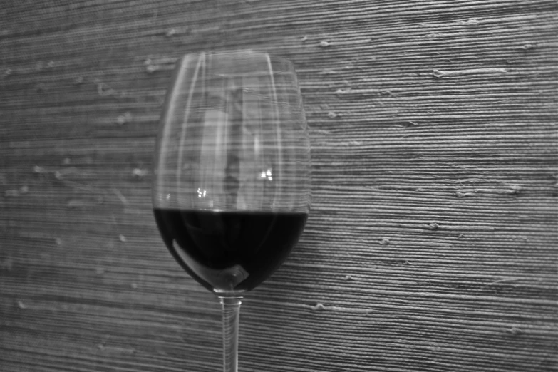 the stem of a wine glass sits next to a wooden wall