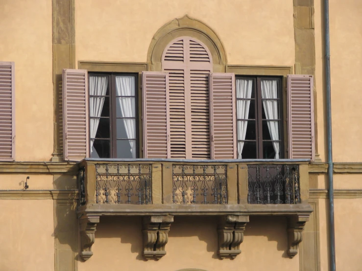 a balcony with two windows and shutters open