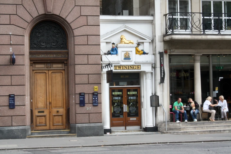 several people sitting at the curb in front of a building