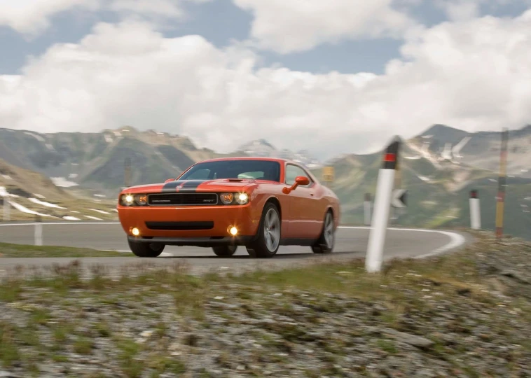 a mustang on the road with mountains in the background