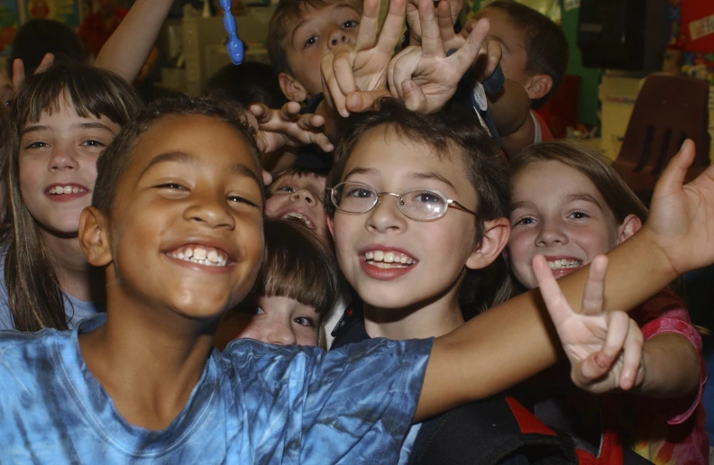 a large group of children standing together and waving