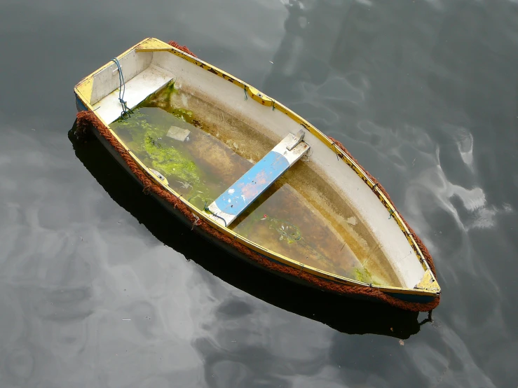 an empty rowboat with no passengers sits alone in the calm water