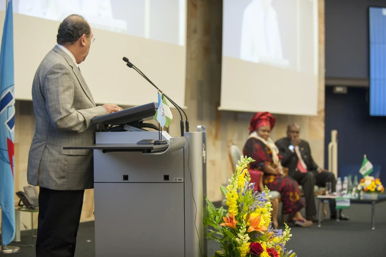 a woman speaking on a podium at a panel of speakers