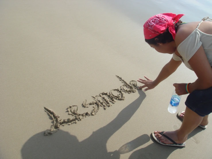 a person writing soing in the sand on the beach