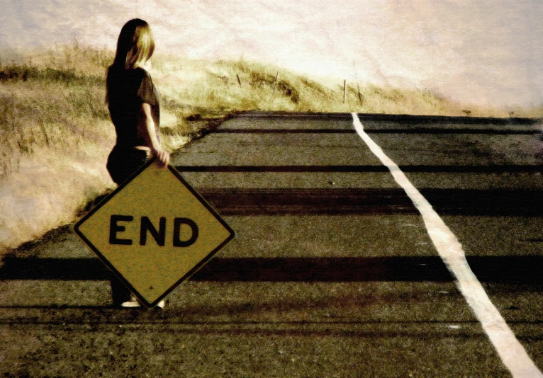 a woman standing on the road with her end sign