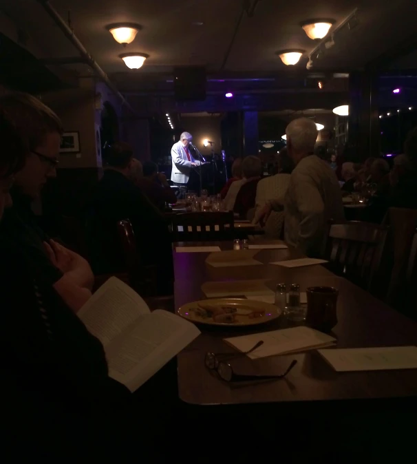 a dining room filled with people sitting at dinner tables eating pizza