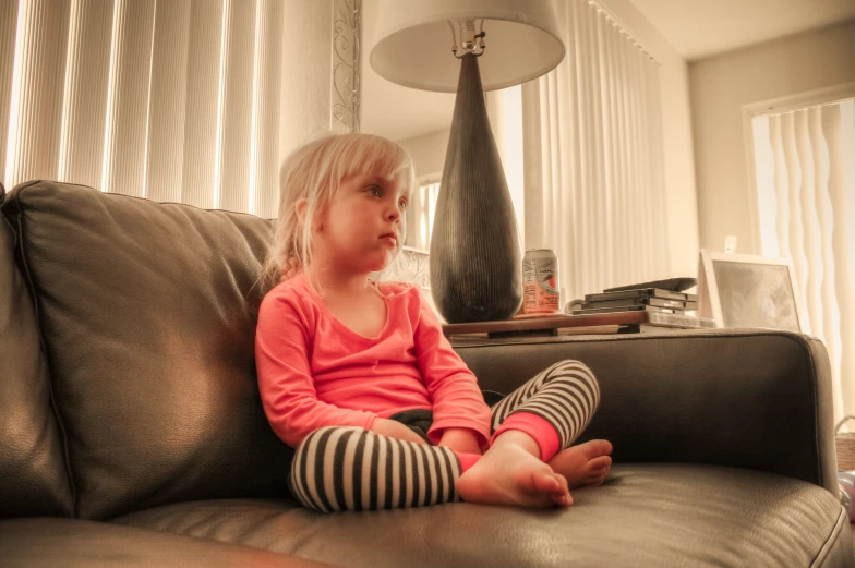 a little girl sitting on top of a couch in a living room