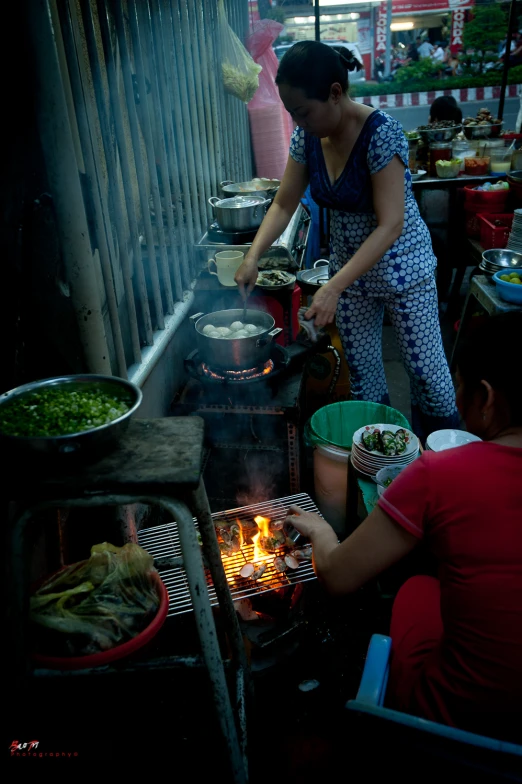 a woman cooking food in a large outdoor grill