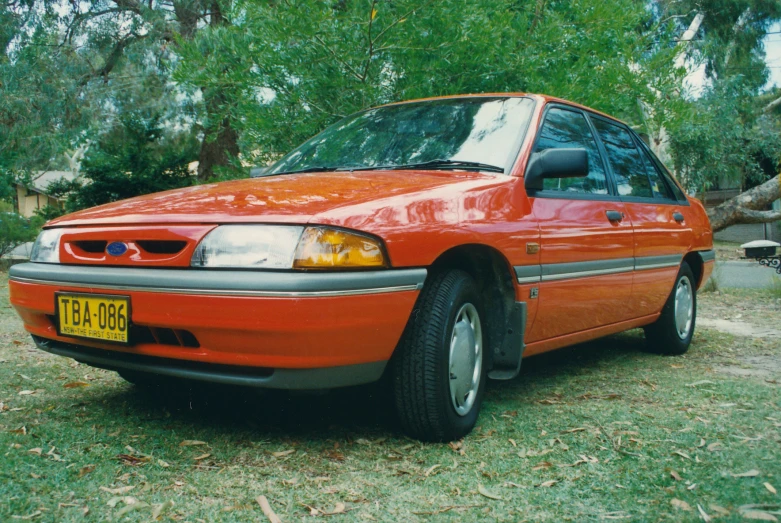 an orange car is parked on a patch of grass