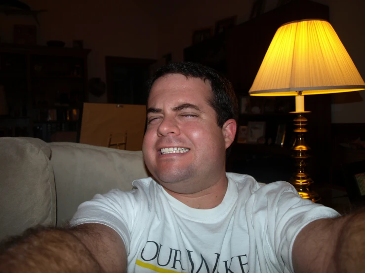 a man with a smile, sitting on a couch and posing for the camera