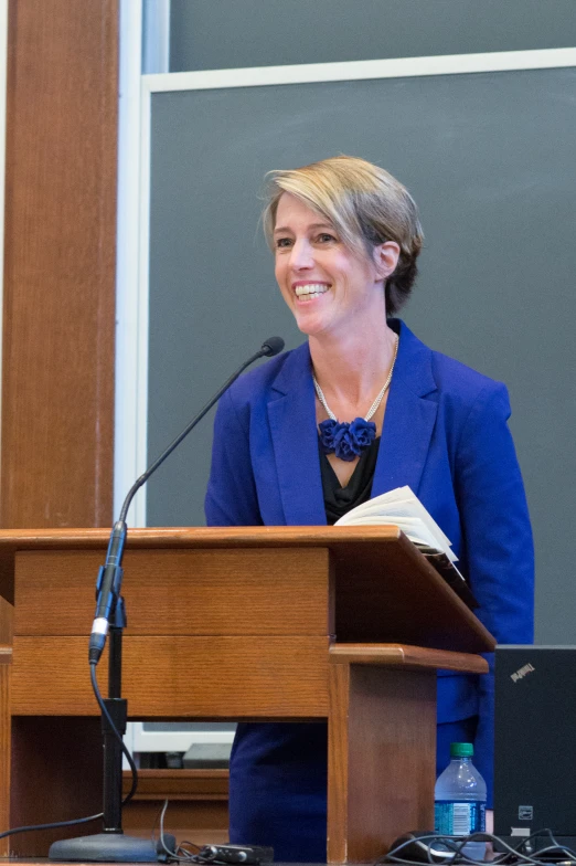 the woman is smiling while she gives a speech