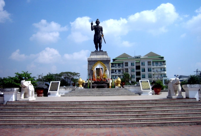 a statue and some stairs and buildings with sky background