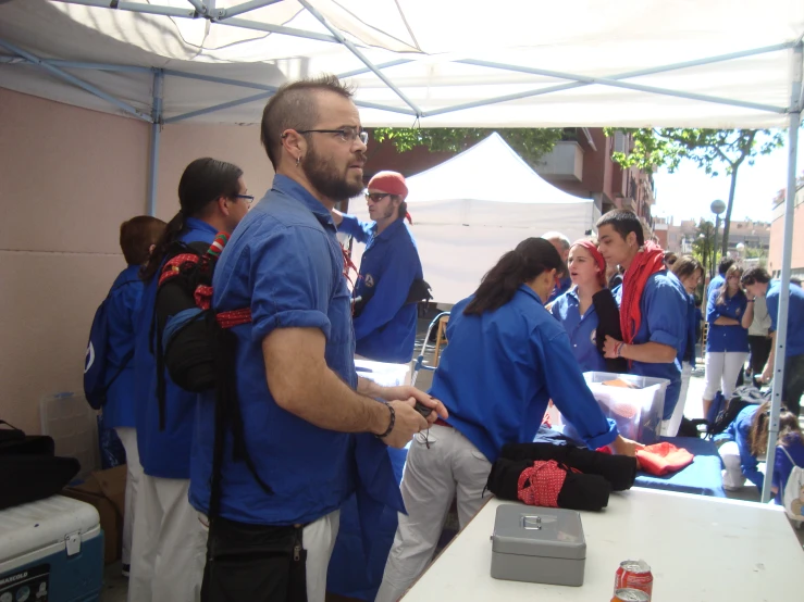 men and women in blue shirts are under tents