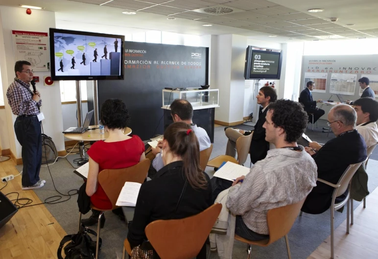 a group of people in a room listening to an instructor