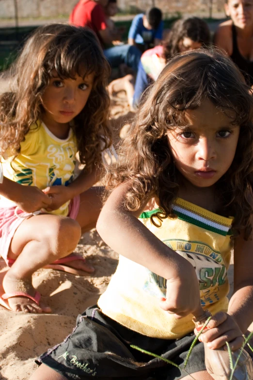 two little girls that are sitting on the sand