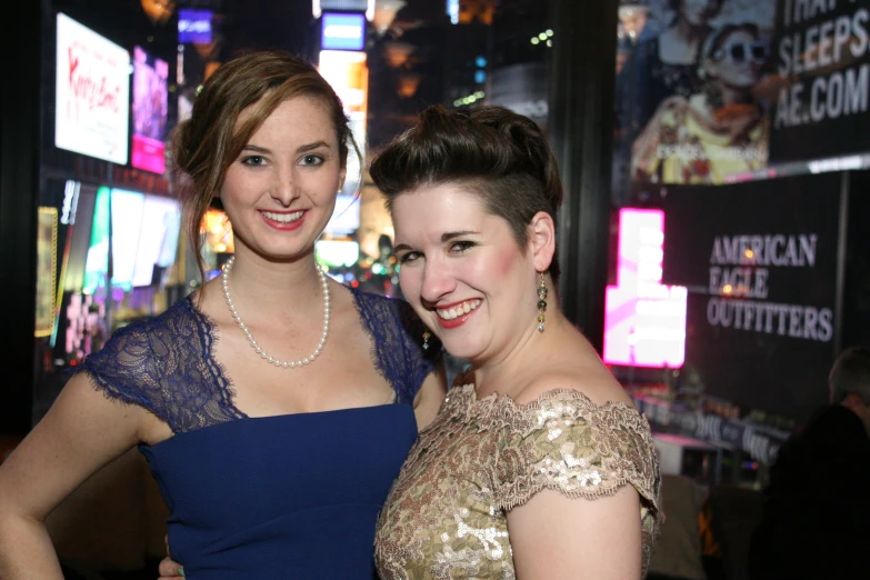 two women pose for a po in front of neon signs