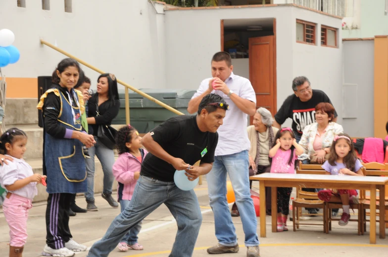 a couple of men are playing table tennis with young children