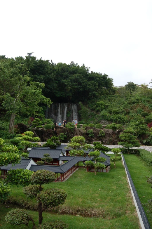 an area with trees and people near a waterfall