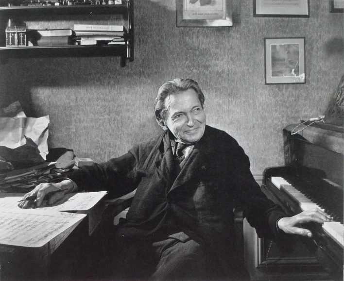 a man wearing a suit sits in front of a piano