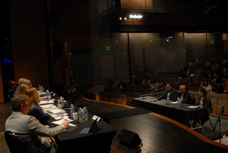 people sitting at tables while the speakers speak into microphones