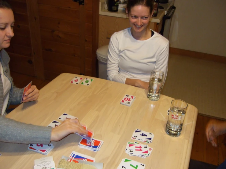 two women sitting at a table playing cards
