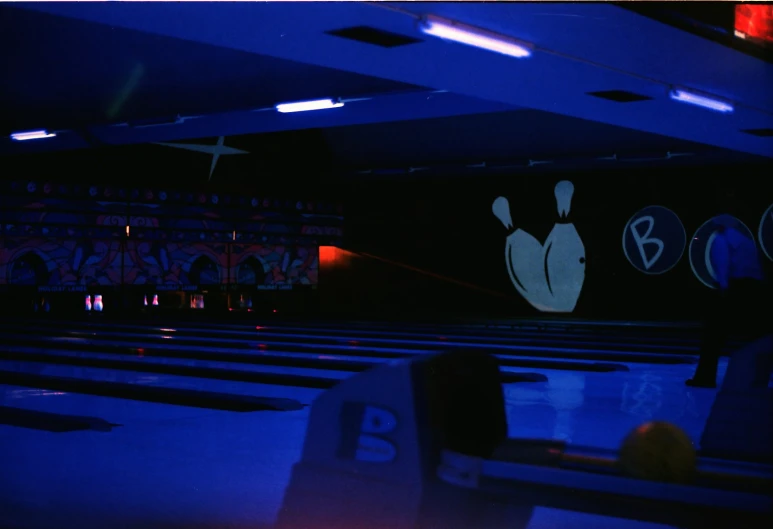 bowling alleys at night with many lanes and bowling balls on the wall