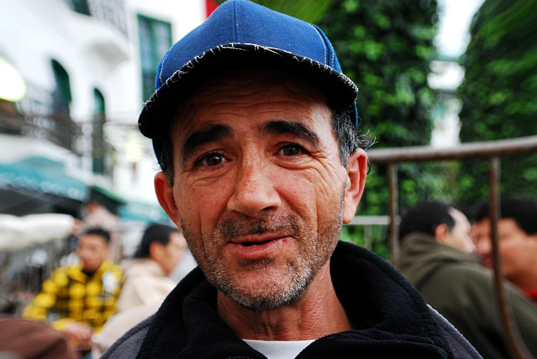 a man with a blue cap on stands next to other people