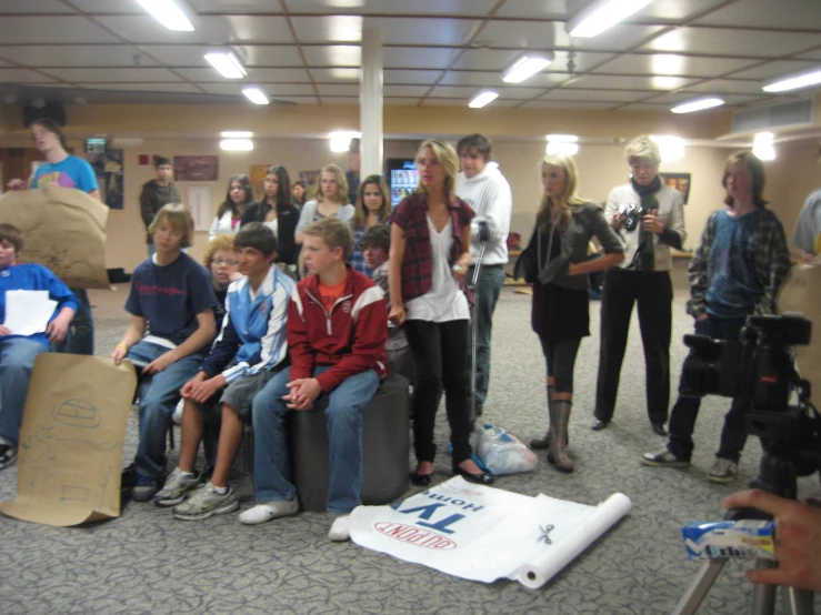 a group of people standing around a room with bags on the floor