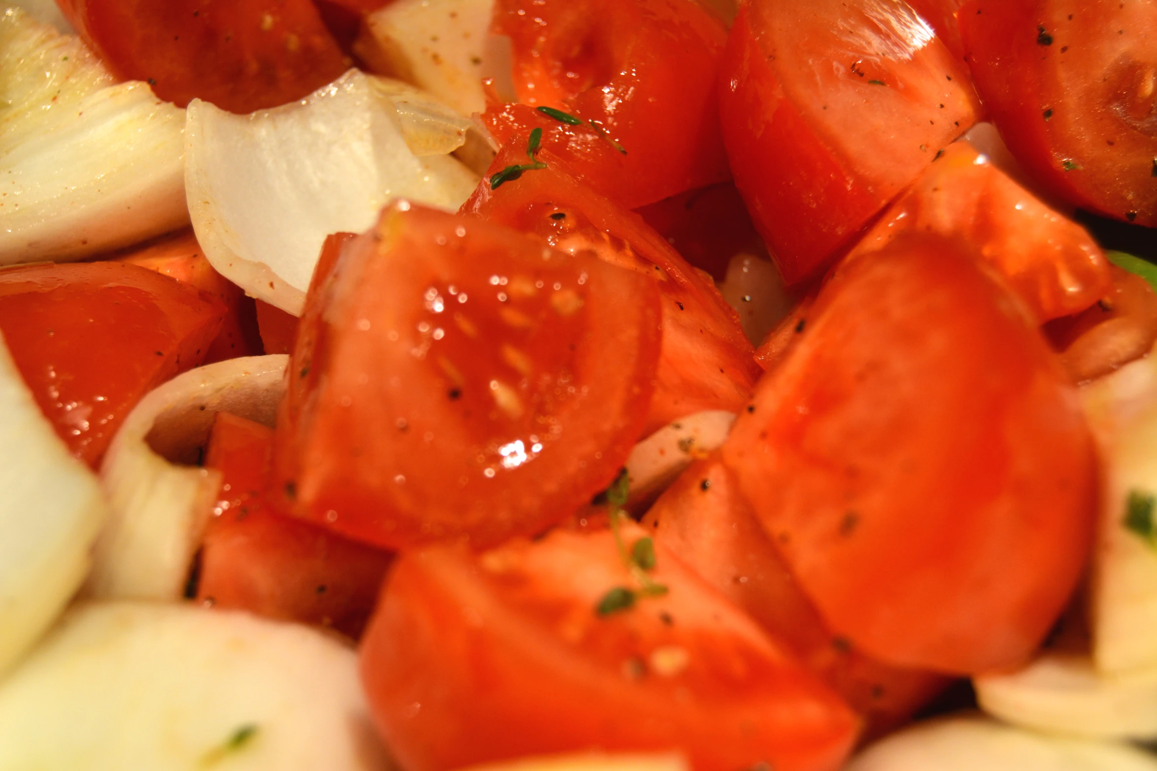 chopped vegetables being stirred with oil in large bowl