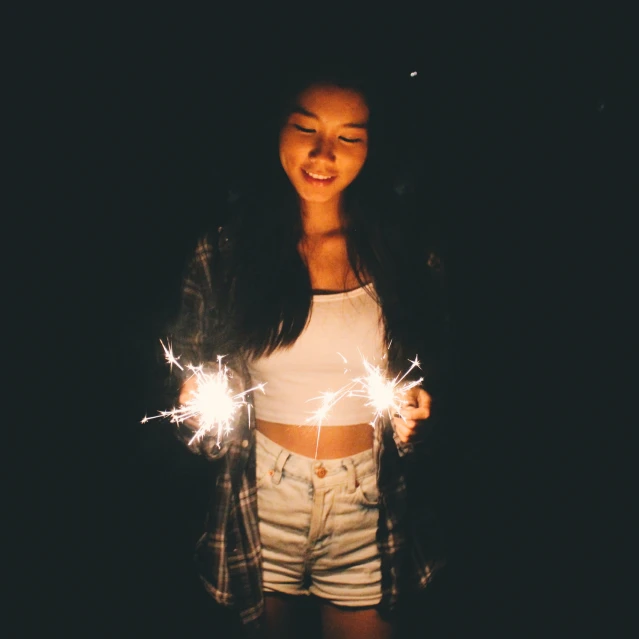 a woman is standing holding sparklers in her hands