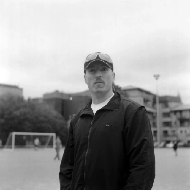 a man wearing a baseball hat is standing near a soccer field