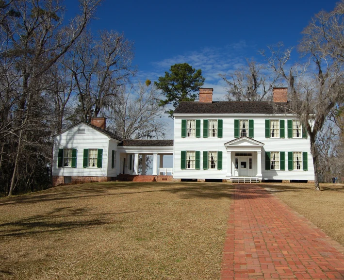 a white house with green shutters stands out in the open