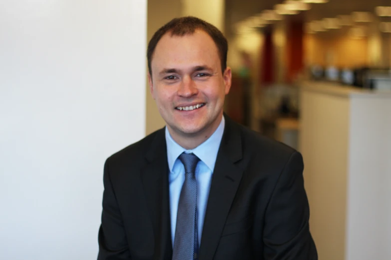 a man is wearing a black jacket and blue tie