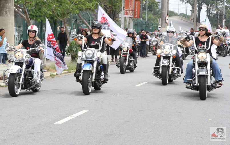 a group of people are riding motorcycles down the street