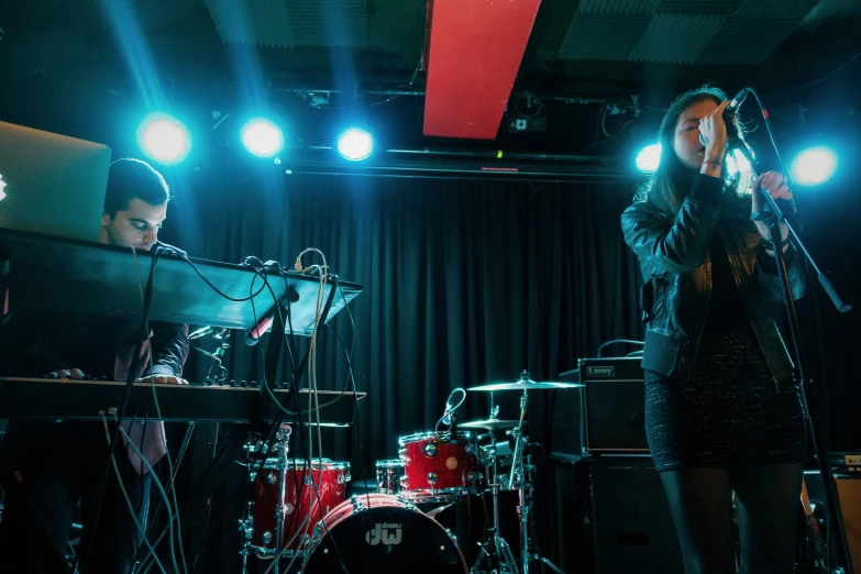 some people standing on stage singing and playing instruments