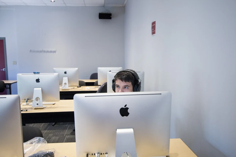 a man wearing headphones sits in front of three computer screens