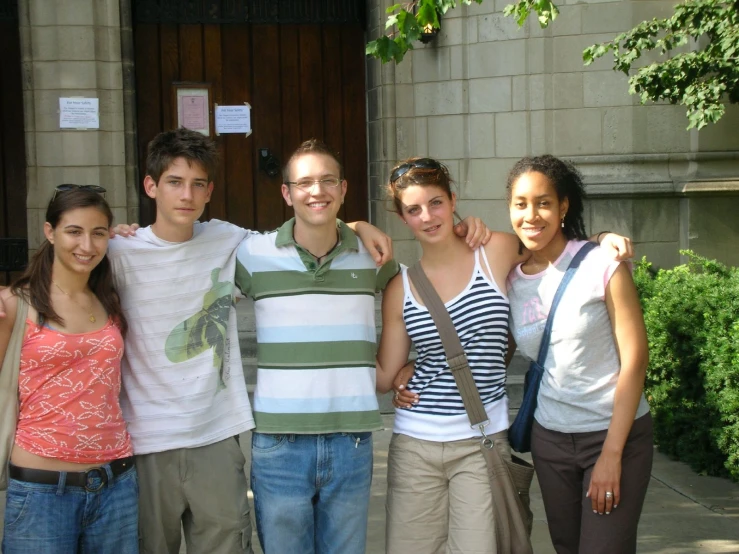 four young people pose together in front of a building