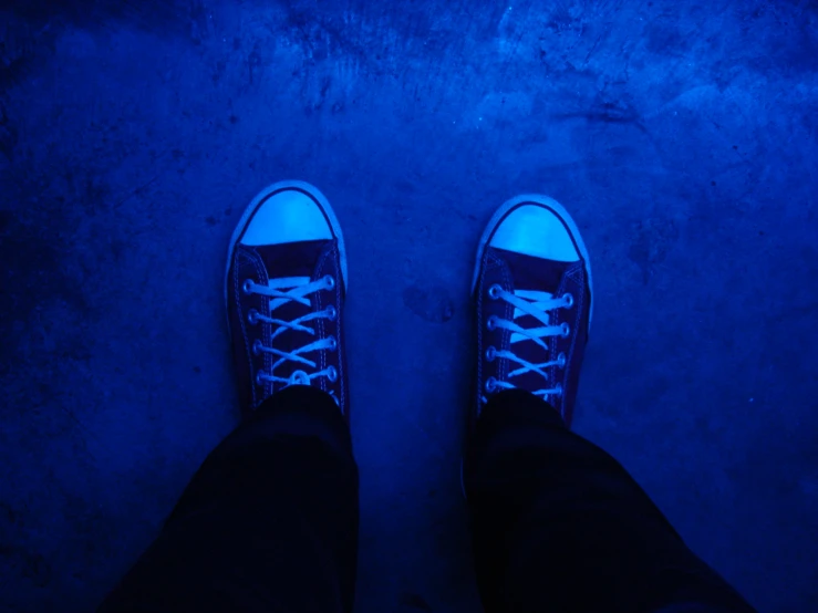 the person has blue shoes on standing in the dark