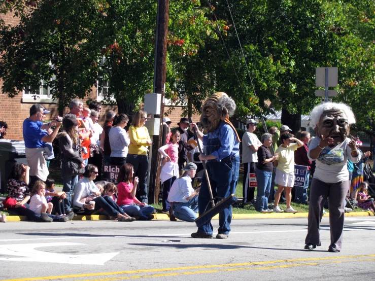 people watching as some sing and others dance on the side of a road