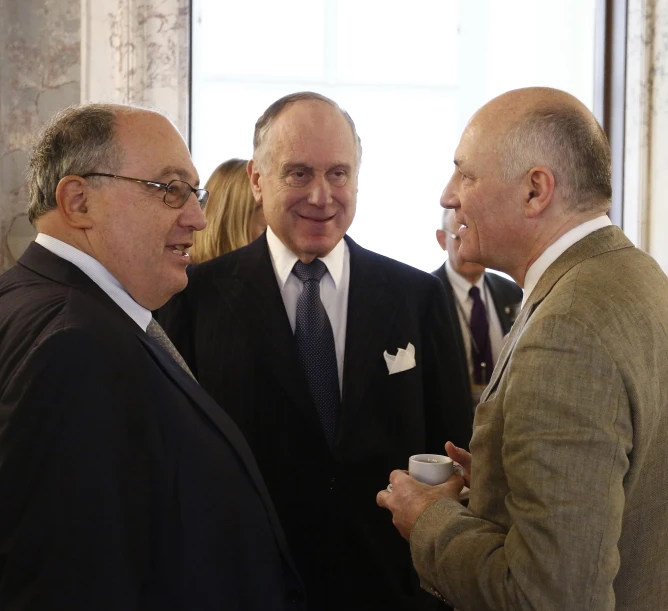 four men are talking with one holding a cup