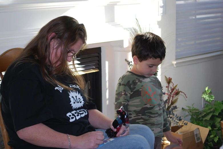 a woman and a boy play with cellphones